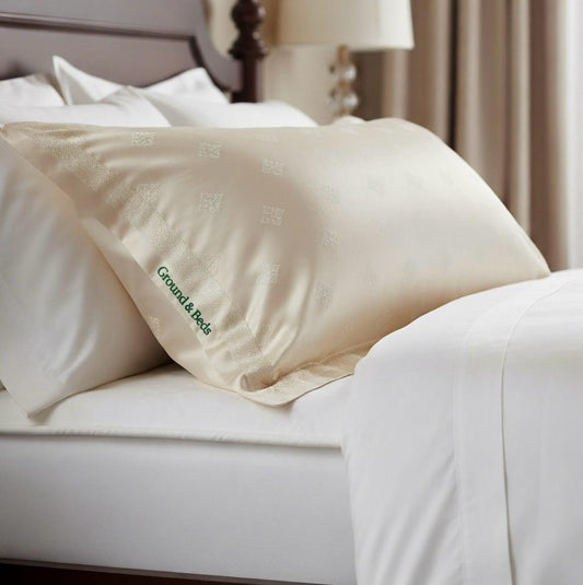 Close-up of a pillow with 'Ground & Bees' branding on a bed.
